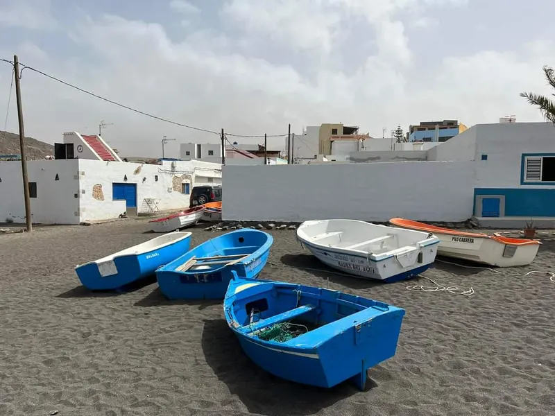 Bunte Fischerboote am dunklen Sandstrand