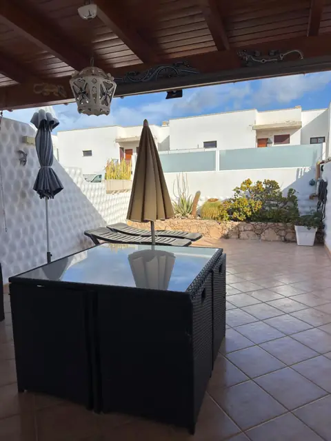 Überdachter Teil der Terrasse mit Sitzgruppe und Sonnenschirm