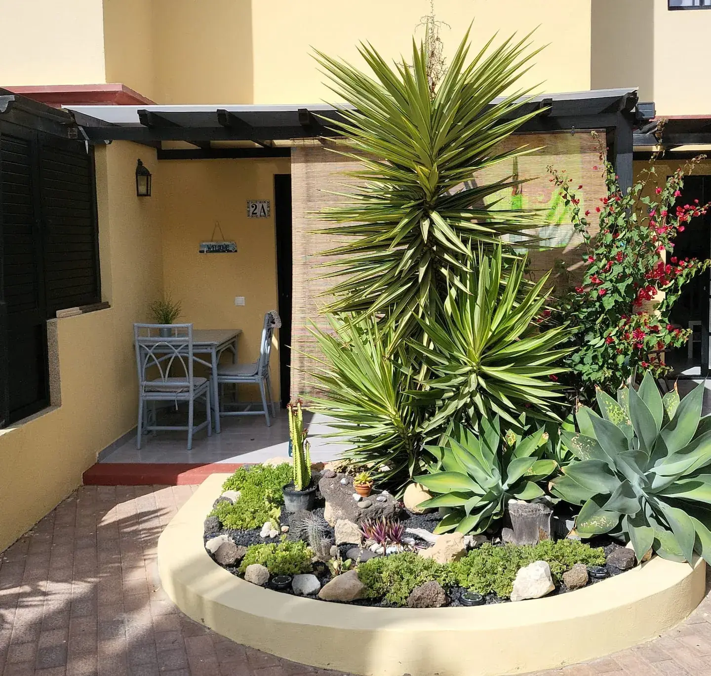Innenhof mit rundem Beet aus Agaven und Palmen vor der Terrasse