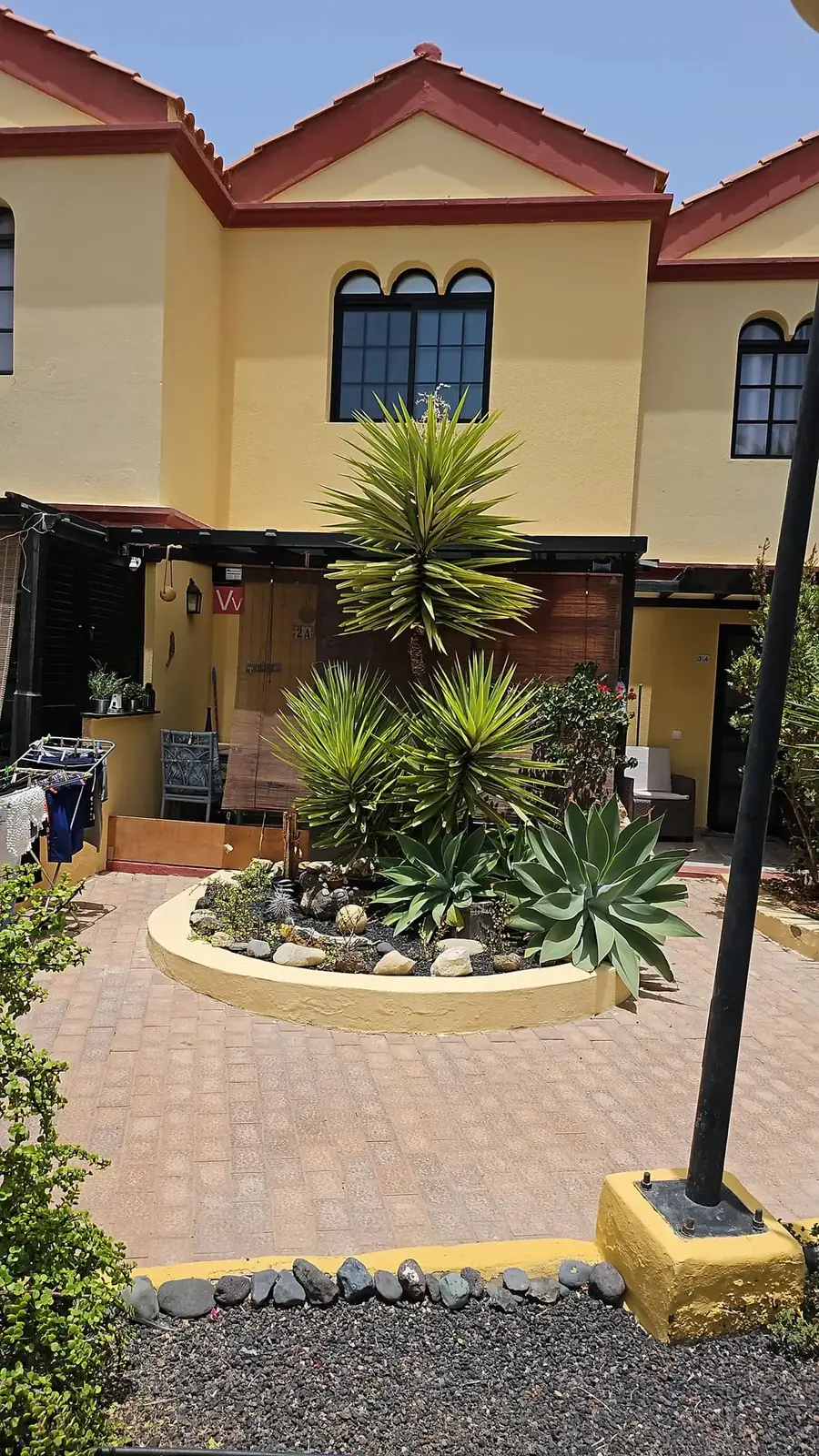 Ockerfarbenes Reihenhaus der Casa Zimbo mit Palmenbeet im Innenhof